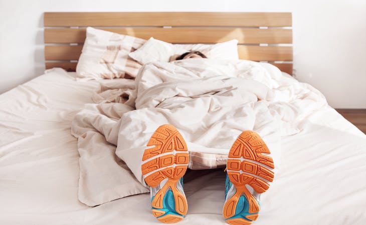 athlete lying on top of mattress with sneakers on