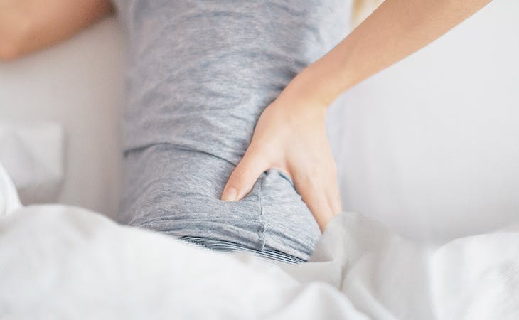 image of a woman touching back in pain - can a mattress cause back pain