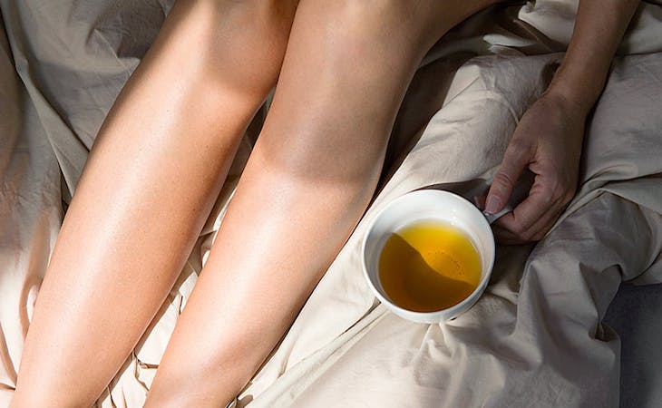 image of woman drinking tea in bed - natural sleep supplements