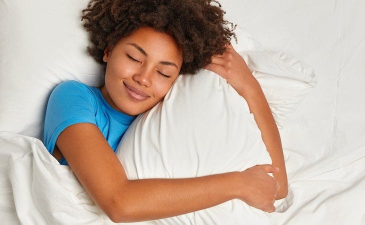 image of person hugging pillow in bed