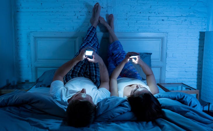 couple in bed on phones in the middle of the night