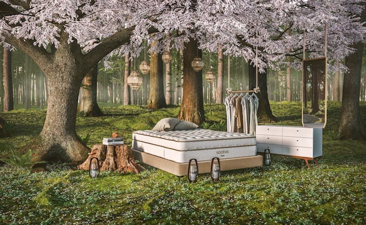 mattress, dresser, and clothing rack outside in forest to symbolize the concept of friluftsliv