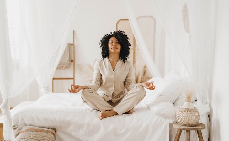 person sitting on top of bed meditating
