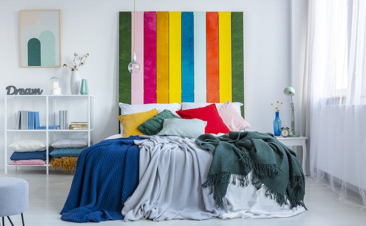 kindercore bedroom with yellow, green, gray, red, and pink pillows on top of bed