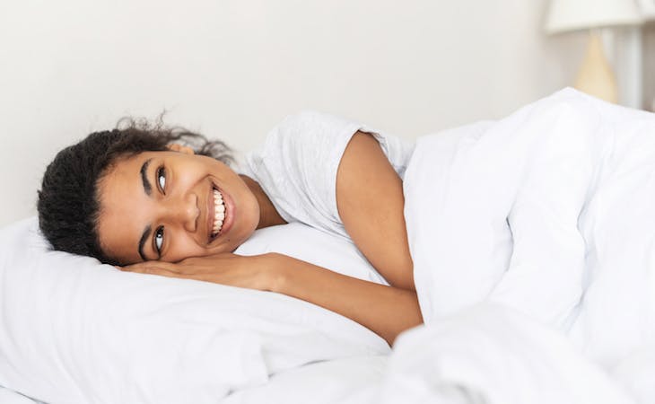 person happy in bed for world sleep day