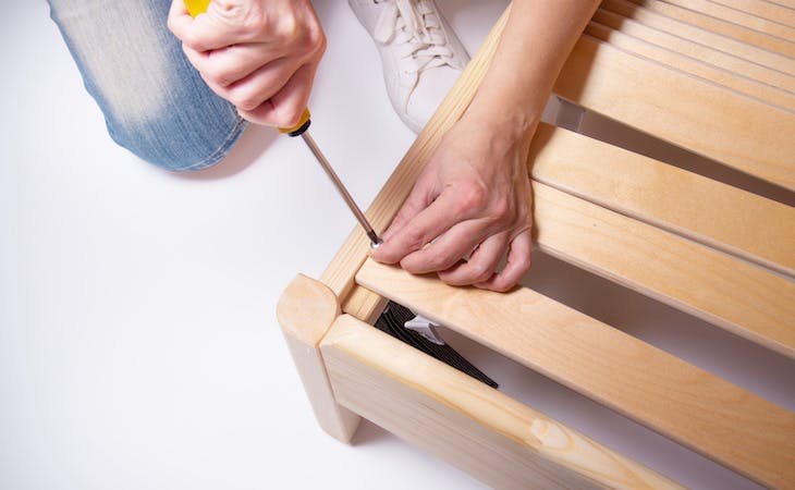 person fixing a squeaky bed frame