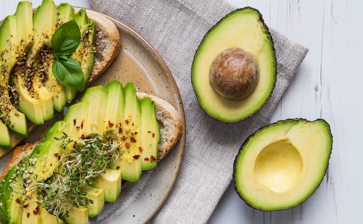 avocado toasts next to cut avocados