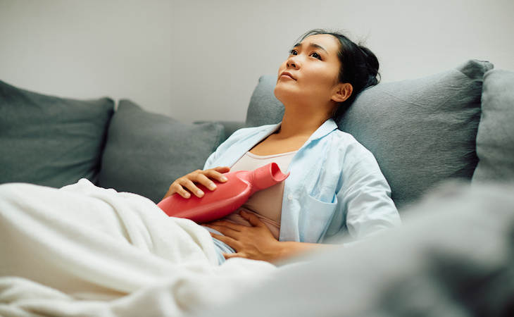 person with endometriosis pain lying down with heating pad