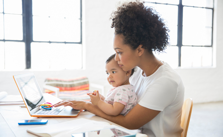 person working on laptop with baby in lap after maternity leave