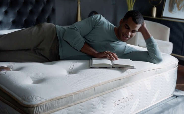 man reading book on top of saatva mattress