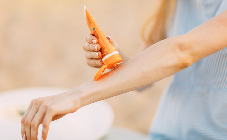 person applying sunscreen to arm to prevent sunburb