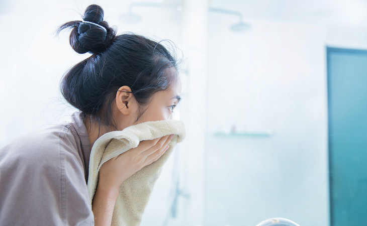person washing face and drying off with towel