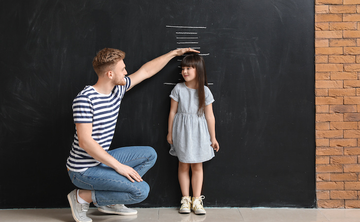 parent measuring child's height against wall