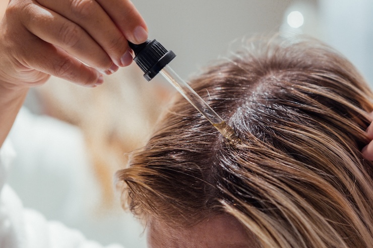 person applying rosemary oil to scalp