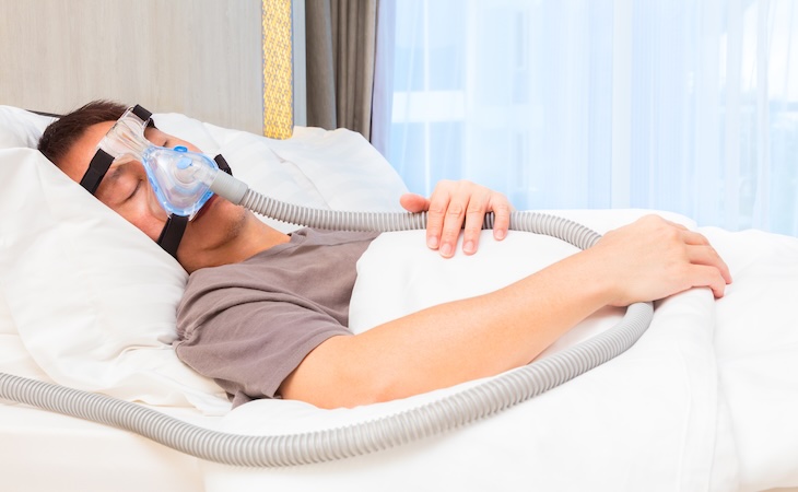 person with hypopnea wearing CPAP, sleeping in bed