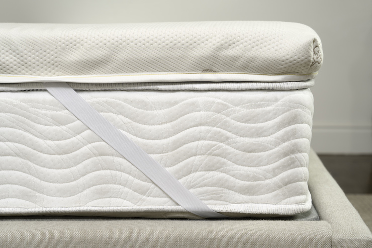 Mattress topper strapped to bed