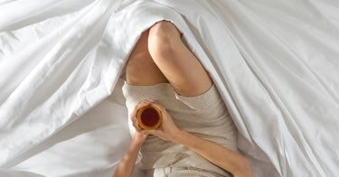 Woman lying comfortably in Saatva sheets.