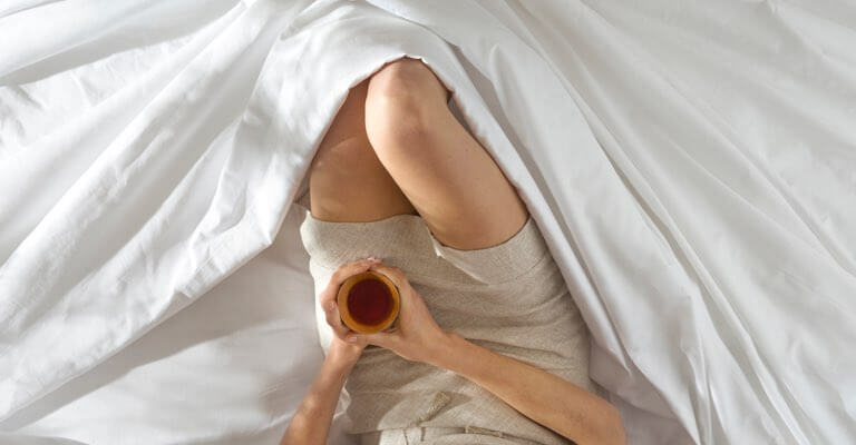 Woman lying comfortably in Saatva Signature Sateen sheets.
