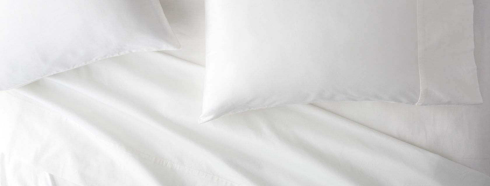 Saatva Signature Sateen sheets and pillows on a bed.