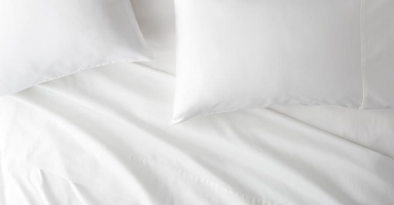 Saatva Signature Sateen sheets and pillows on a bed.